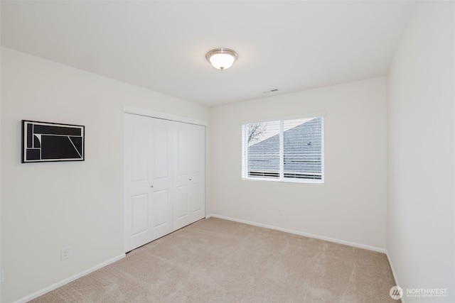 unfurnished bedroom with light carpet, visible vents, baseboards, and a closet