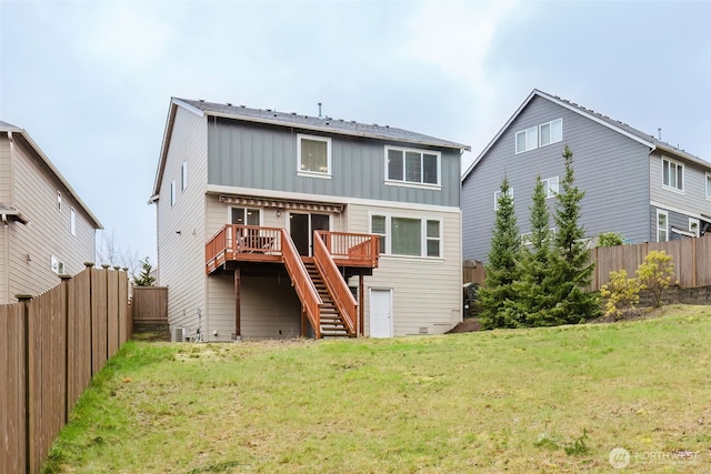 back of property with a deck, fence, a yard, stairway, and board and batten siding