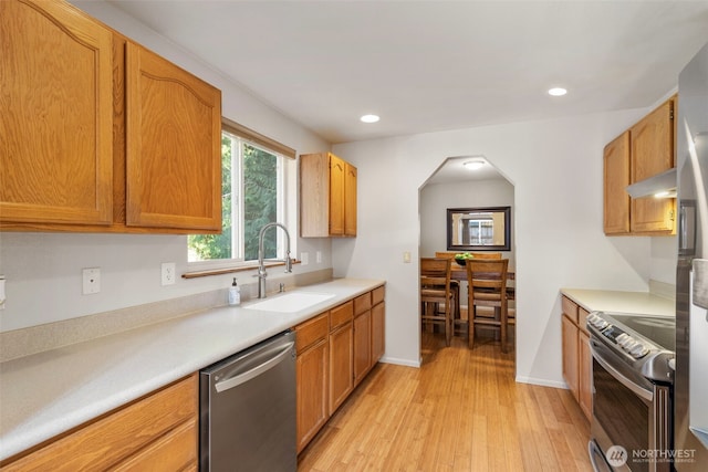 kitchen featuring light wood finished floors, stainless steel appliances, recessed lighting, light countertops, and a sink