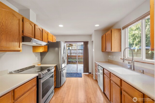 kitchen featuring under cabinet range hood, appliances with stainless steel finishes, light countertops, and a sink