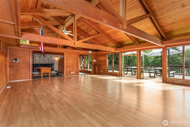 unfurnished living room with wooden ceiling, wood walls, beamed ceiling, and wood finished floors