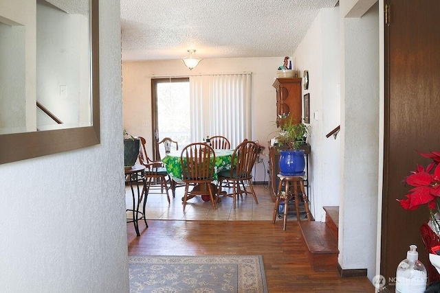 dining room with a textured ceiling, stairs, a textured wall, and wood finished floors