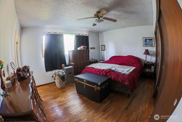 bedroom with ceiling fan, baseboards, a textured ceiling, and wood finished floors