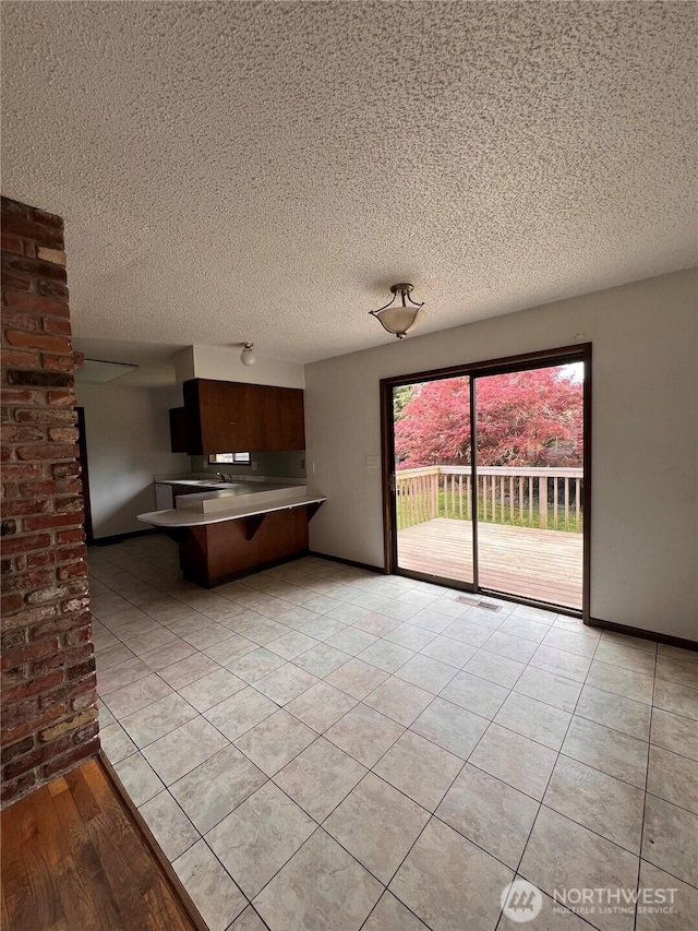2109 Ontario St, Bellingham, WA 98229 - kitchen featuring a breakfast bar area, a textured ceiling, baseboards, light tile patterned flooring, and a peninsula