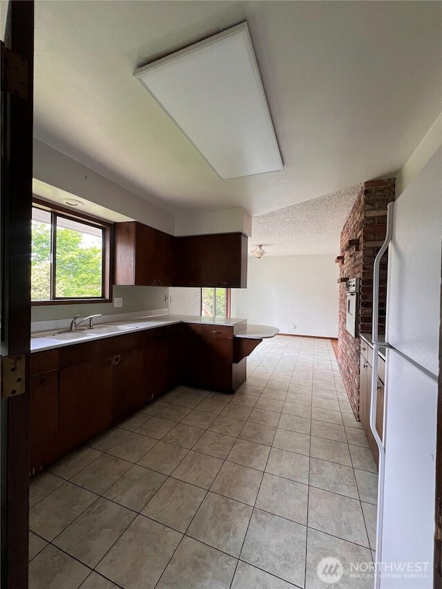 2109 Ontario St, Bellingham, WA 98229 - kitchen featuring freestanding refrigerator, light tile patterned floors, dark brown cabinets, a sink, and light countertops