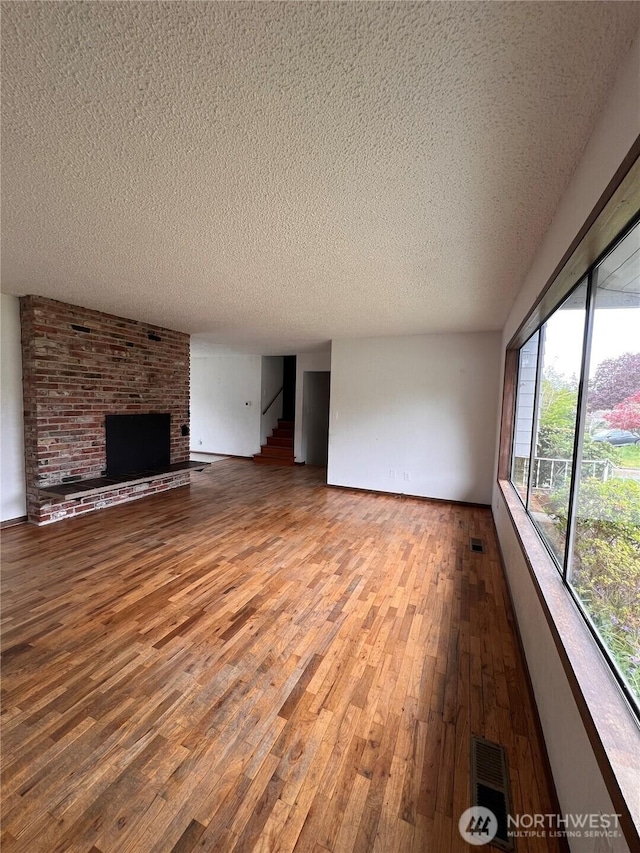 2109 Ontario St, Bellingham, WA 98229 - unfurnished living room featuring a brick fireplace, visible vents, a textured ceiling, and wood finished floors