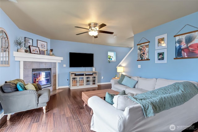 living area with ceiling fan, baseboards, wood finished floors, and a tiled fireplace