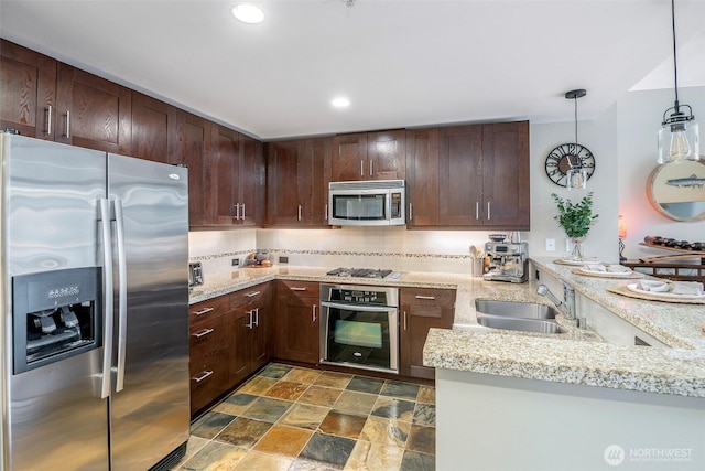 kitchen featuring light stone counters, stainless steel appliances, a peninsula, a sink, and tasteful backsplash