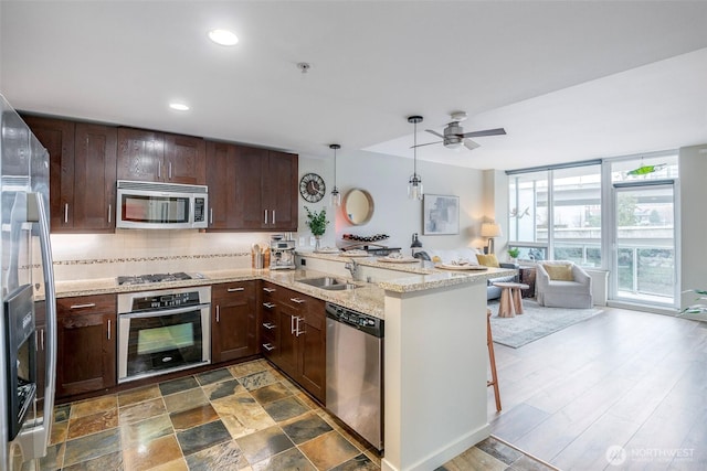 kitchen with decorative backsplash, appliances with stainless steel finishes, open floor plan, dark brown cabinetry, and a peninsula