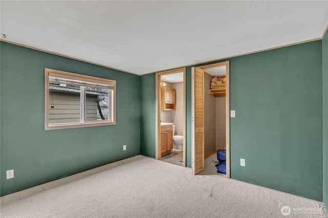 unfurnished bedroom featuring carpet floors, a closet, a spacious closet, and ensuite bath