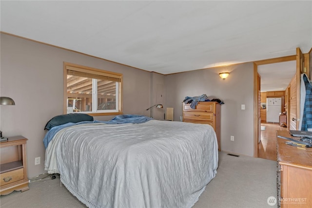 bedroom with light carpet, visible vents, and freestanding refrigerator