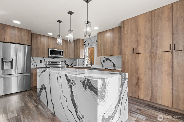 kitchen featuring appliances with stainless steel finishes, dark wood finished floors, decorative light fixtures, and a kitchen island