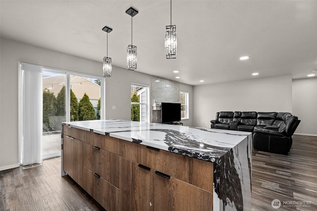 kitchen featuring recessed lighting, a spacious island, light stone countertops, dark wood-style floors, and modern cabinets