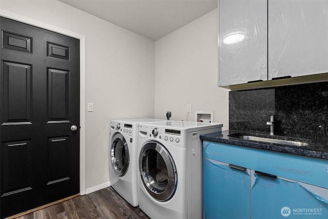 laundry room with dark wood-style floors, cabinet space, a sink, and washing machine and clothes dryer