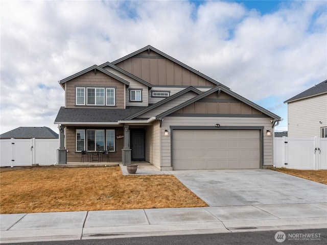 craftsman inspired home featuring board and batten siding, a gate, an attached garage, and concrete driveway