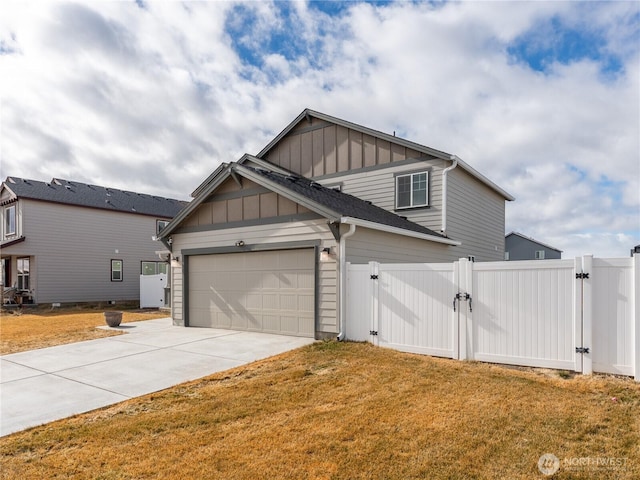 view of side of home with an attached garage, driveway, a lawn, a gate, and board and batten siding