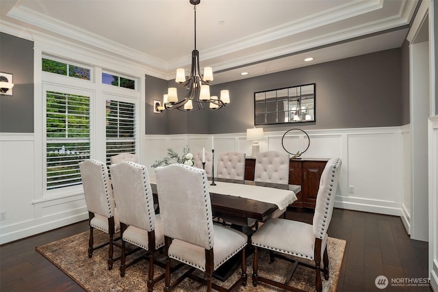 dining room featuring a chandelier, wainscoting, crown molding, dark wood finished floors, and a decorative wall
