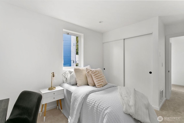 bedroom featuring light carpet, visible vents, baseboards, and a closet