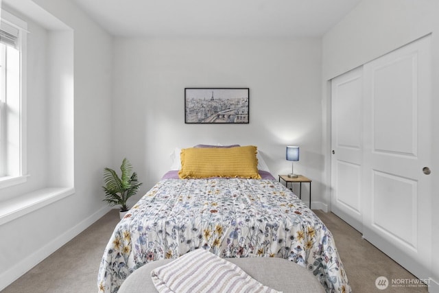 carpeted bedroom featuring a closet and baseboards