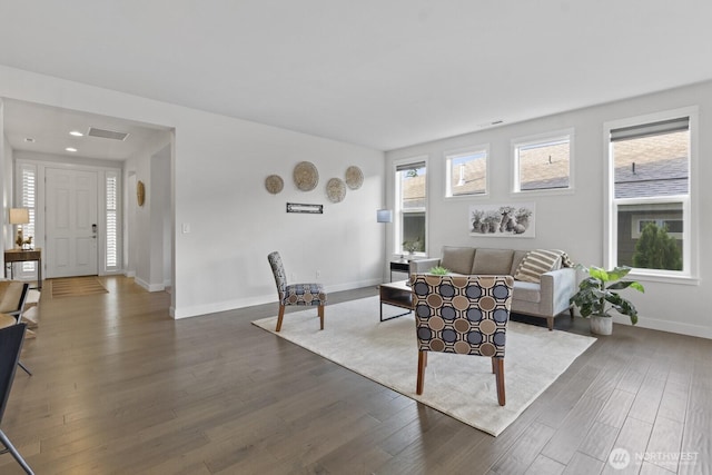 living area with dark wood-style flooring, visible vents, and baseboards