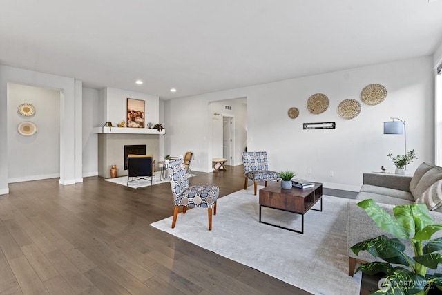 living area with a fireplace with flush hearth, baseboards, dark wood finished floors, and recessed lighting