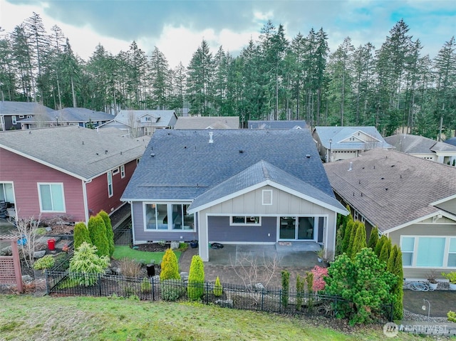 rear view of property with roof with shingles, board and batten siding, a patio, and fence private yard