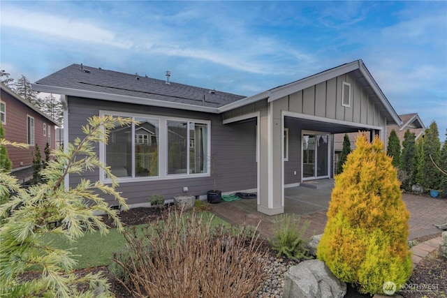 back of property with board and batten siding and a patio area