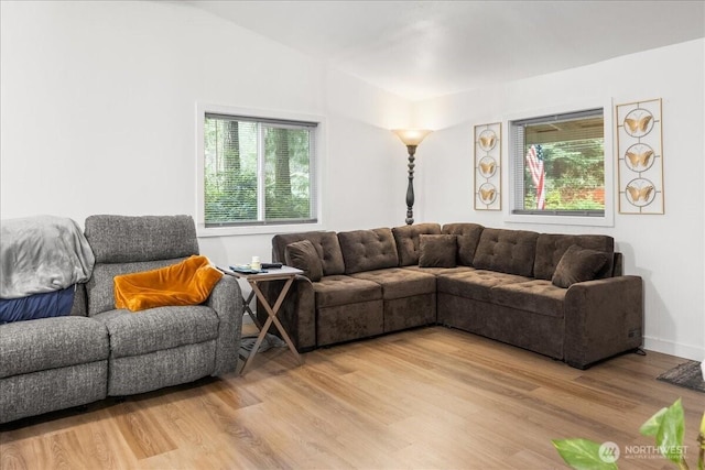 living room with light wood-style floors, lofted ceiling, and baseboards