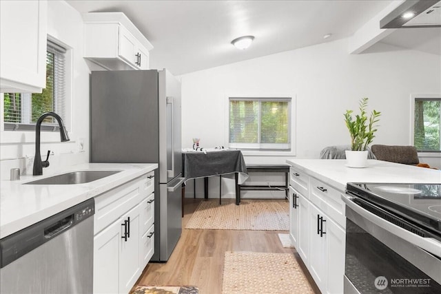 kitchen featuring lofted ceiling, a sink, light countertops, appliances with stainless steel finishes, and light wood-type flooring