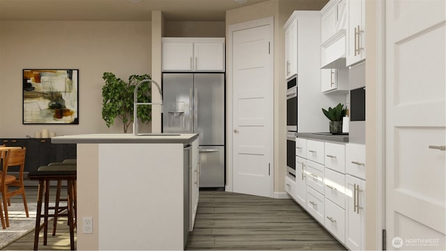 kitchen with a breakfast bar area, dark wood-type flooring, a sink, white cabinets, and appliances with stainless steel finishes