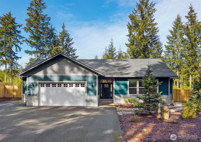 ranch-style house featuring an attached garage, fence, and aphalt driveway