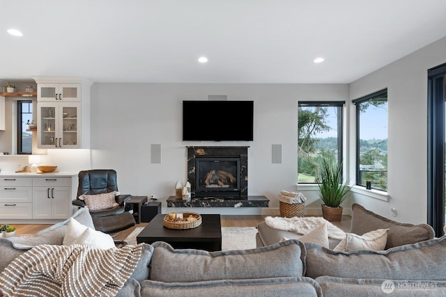 living room with light wood-type flooring, a high end fireplace, and recessed lighting