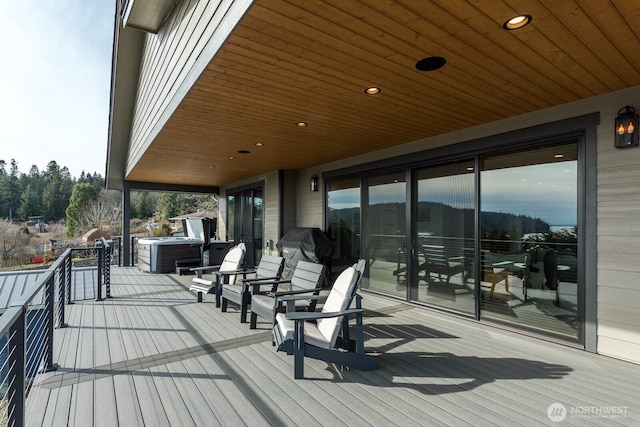 wooden deck featuring a hot tub and a grill