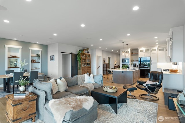 living room with light wood-style floors, recessed lighting, and a barn door