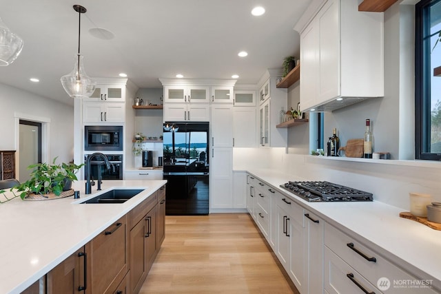 kitchen featuring black appliances, open shelves, a sink, and light countertops