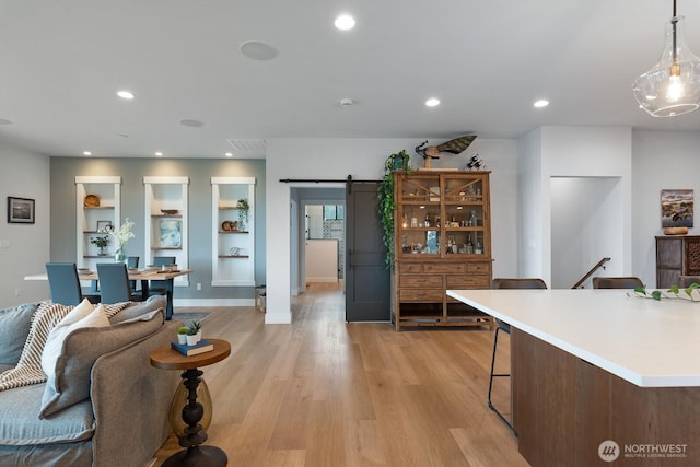 kitchen with recessed lighting, light countertops, light wood-style flooring, and a barn door