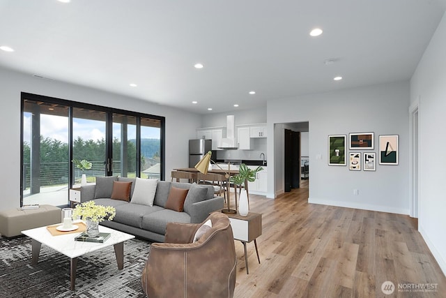 living area featuring baseboards, light wood finished floors, and recessed lighting