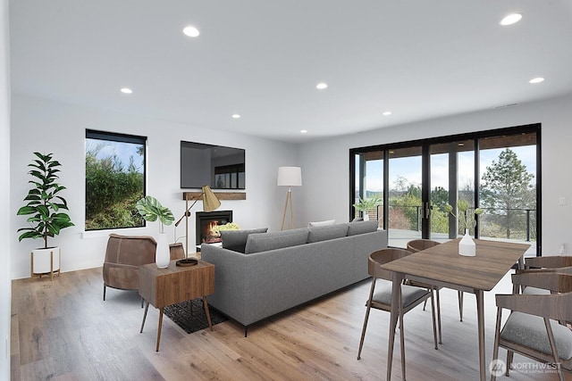 living area with recessed lighting, french doors, a glass covered fireplace, and light wood-style flooring