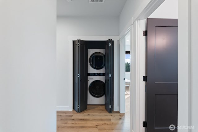 corridor with stacked washer and dryer, visible vents, and light wood finished floors