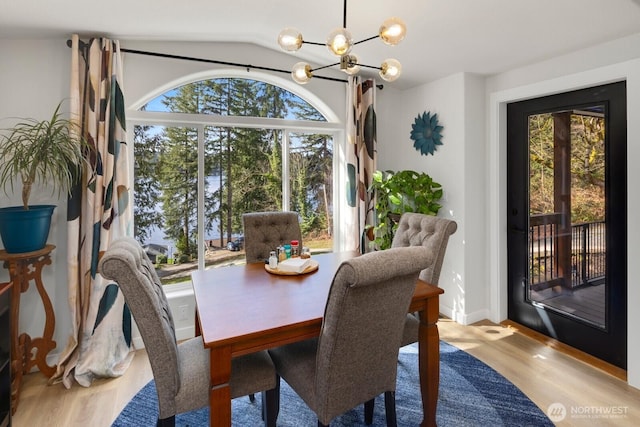 dining space featuring a chandelier, lofted ceiling, and wood finished floors