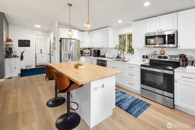 kitchen featuring tasteful backsplash, light wood-style flooring, a breakfast bar area, appliances with stainless steel finishes, and a sink