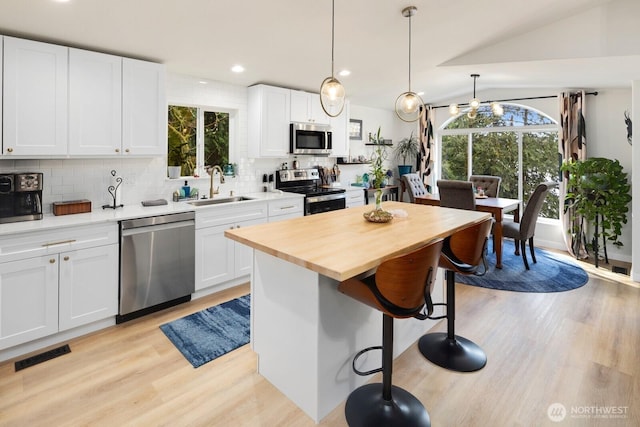 kitchen featuring a sink, visible vents, a kitchen breakfast bar, appliances with stainless steel finishes, and tasteful backsplash