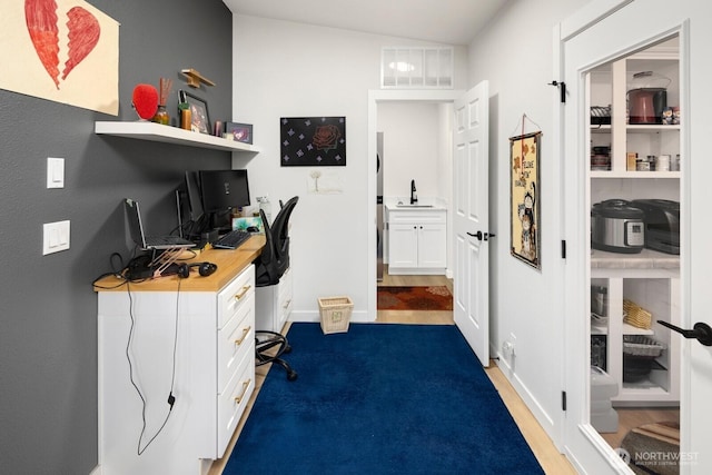 office area featuring visible vents, a sink, baseboards, and wood finished floors