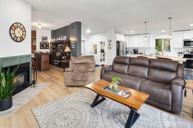 living area with a fireplace with flush hearth, recessed lighting, and light wood finished floors