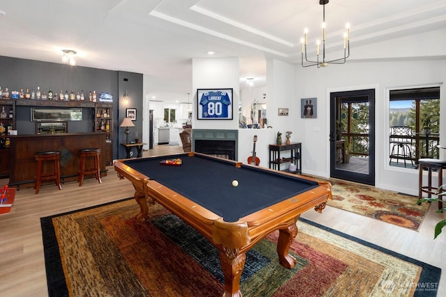 rec room featuring a dry bar, wood finished floors, pool table, a tray ceiling, and a fireplace