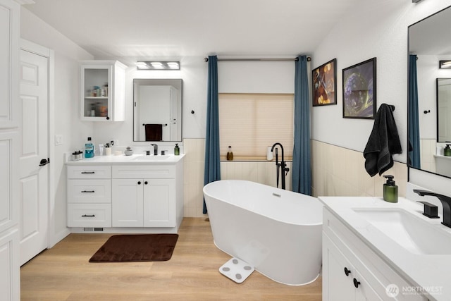 bathroom featuring a freestanding tub, a sink, and a wainscoted wall