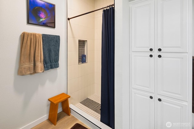 bathroom featuring a stall shower, baseboards, and wood finished floors