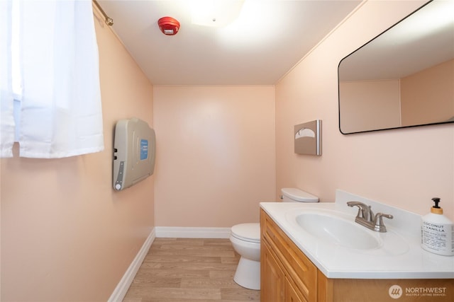 bathroom with baseboards, vanity, toilet, and wood finished floors