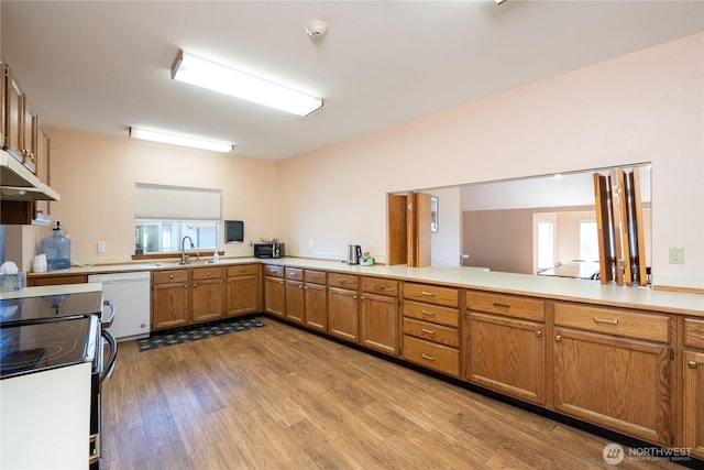 kitchen featuring brown cabinetry, light countertops, dishwasher, and a peninsula