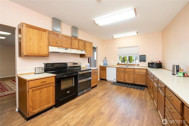kitchen with black electric range oven, a peninsula, white dishwasher, light countertops, and under cabinet range hood